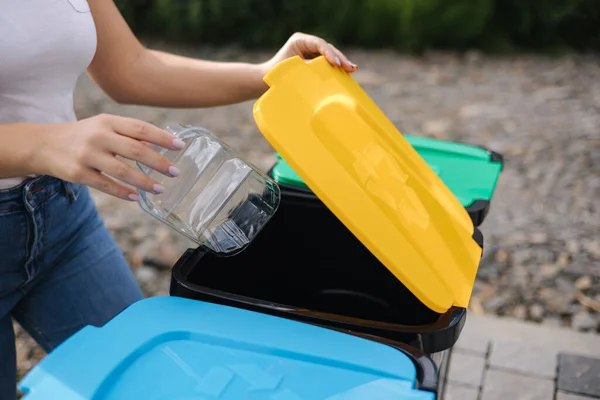Vicino di femmina buttare nel cestino di riciclaggio pulito contenitore di plastica vuoto. Diverso colore dei bidoni di riciclaggio — Foto Stock