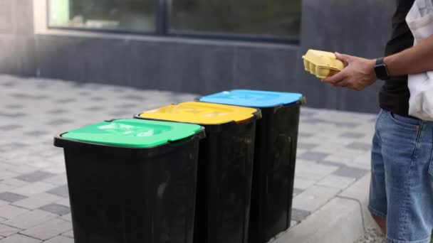 Man met eco-pakket voor afval brengen afval naar recycling bakken outddors. Concept van recycling — Stockvideo