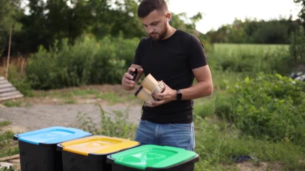 Facet wyrzucający jednorazowy kubek do kosza na śmieci. Atrakcyjne młody facet oddzielne plactic pokrywa z kartonowym kubkiem i thow do innego kosza — Wideo stockowe