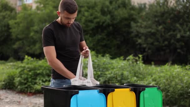 Junger Mann entnimmt Öko-Verpackungsmüll und legt ihn in Recyclinghöfe. Konzept des Recyclings. Baumbehälter, grün, gelb und blau. Frau steckte andere Art von Rabauken in Müllcontainer — Stockvideo