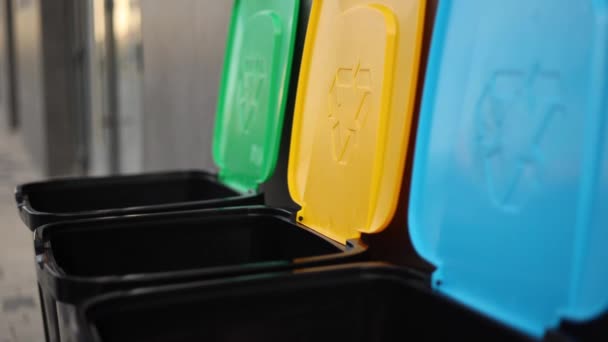 ごみ箱にプラスチック容器を投げる女性のクローズアップ。屋外のリサイクルビンの異なる色。女性の側面図は、容器にゴミを入れ — ストック動画