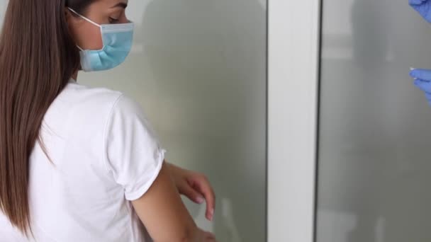 의료용 마스크를 쓴 여자가 Covid-19 에 탑승 한다. 병원에서 독감 백신을 맞았어요. 전문 간호사가 여성 환자에게 항 바이러스 주사를 한대. 예방 접종, 질병 예방 개념. 가까이 서 본 모습 — 비디오