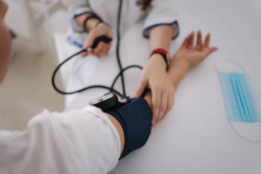Doktorun steteskopla sphygmomanometre kullanarak kan basıncını ölçtüğü yakın plan.