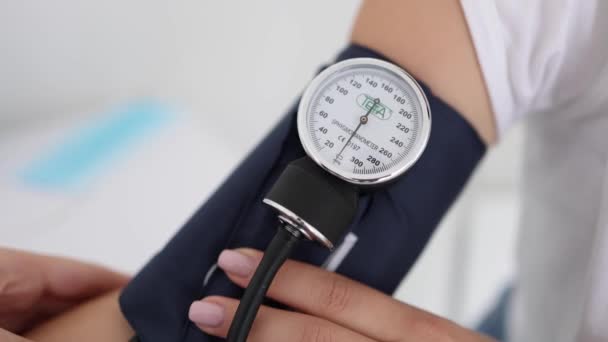 Close-up of doctor using sphygmomanometer with stethoscope checking blood pressure to a female patients in the clicic — Stok Video