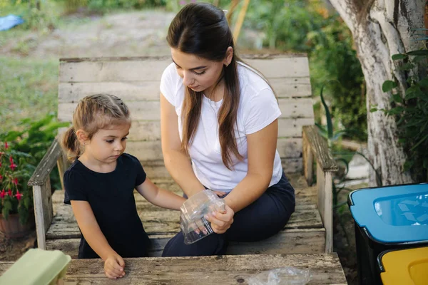 A család szemetet rendez otthon az udvaron. Az újrahasznosítás fogalma a szabadban. Anya és lánya törődik a természettel. — Stock Fotó