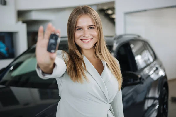 Foto av attraktiv och ung affärskvinna i bilsalongen. Kvinnliga hålla nycklar från hennes nya bil — Stockfoto