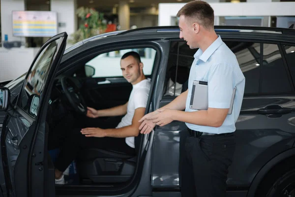 Salesperson selling cars at car dealership. Man choosing car in car showroom