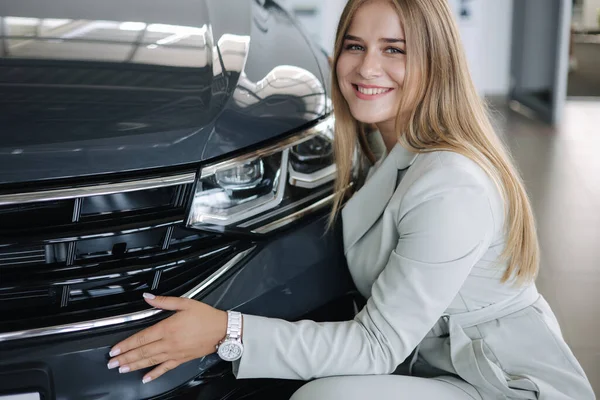 Mulher de negócios escolhendo um carro novo em um showroom de carro. Abraço feminino feliz carro novo e muito feliz — Fotografia de Stock