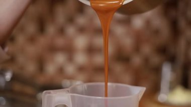 Kadının yakın çekimi tuzlanmış karameli plastik kabın içine boşaltıyor.