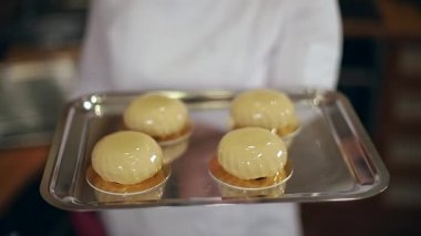 Beyaz Kittel 'deki kadın pastacı mutfakta lezzetli bir tatlı ile süslenmiş. Pembe eldivenli eller, tatlılığı ve çalışmayı tutun.