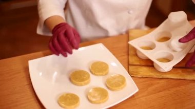 Eldivenli profesyonel bir şekerci tabaktaki dondurucu parçalarını koyuyor.