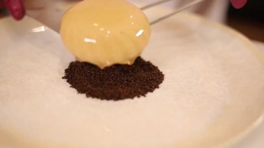 Beyaz Kittel 'deki kadın pastacı mutfakta lezzetli bir tatlı ile süslenmiş. Pembe eldivenli eller, tatlılığı ve çalışmayı tutun.