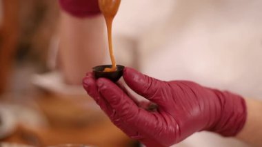 Beyaz Kittel 'deki kadın pastacı mutfakta lezzetli bir tatlı ile süslenmiş. Pembe eldivenli eller, tatlılığı ve çalışmayı tutun.