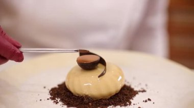 Beyaz Kittel 'deki kadın pastacı mutfakta lezzetli bir tatlı ile süslenmiş. Pembe eldivenli eller, tatlılığı ve çalışmayı tutun.