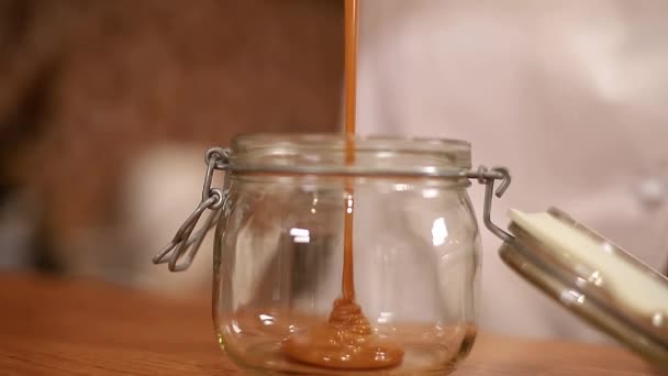 Close-up of woman pours salted caramel into glass container — Stock Video