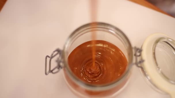 Närbild av kvinnan häller saltad karamell i glasbehållare — Stockvideo