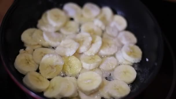 En kvinnlig stuvning av en banan i en skillet. Karamellisering av bananer — Stockvideo