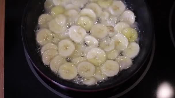 O processo da mulher guisou uma banana em uma frigideira. Caramelização da banana — Vídeo de Stock