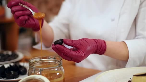 Confeiteiro feminino em kittel branco decorado sobremesa saborosa na cozinha. Fechar-se de mãos em luvas rosa mantém a doçura e o trabalho — Vídeo de Stock