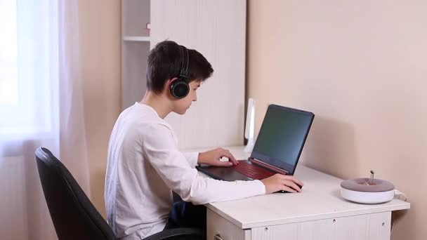 十几岁的男孩在他的电脑上的白色房间里玩游戏。游戏玩家在笔记本电脑上的网络摄像头上捕获视频 — 图库视频影像