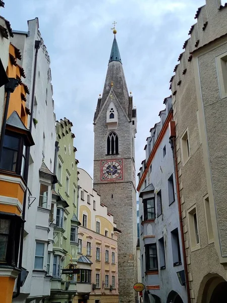 Bressanone, South Tyrol, Italy - June 11, 2024: View of the high Gothic tower of the parish church of Saint Michael and colorful ancient buildings in the historic center of the city