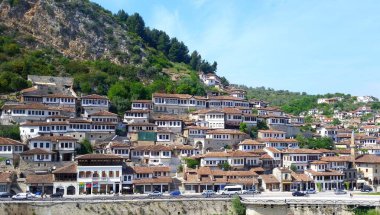 Berat, Arnavutluk - 3 Mayıs 2017: Osmanlı mimarisinin beyaz cepheli ve kahverengi kiremit çatılı eski tarihi evlerinin panoraması