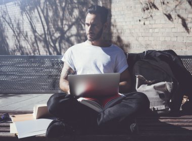 Fotoğraf adam şehir parkı oturan ve mesaj defteri mesajlaşma. Üniversitede okumak, sınavlara hazırlanmak. Kitap, genel tasarım dizüstü bilgisayar, kablosuz internet kullanma. Yatay mockup