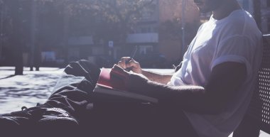 Fotoğraf adam öğrenci kampüsünde oturan ve mesaj not defteri mesajlaşma. Üniversitede okumak, proje de çalışmak, sınava hazırlanmak. Kitap, genel tasarım dizüstü bilgisayar kullanma. Geniş mockup