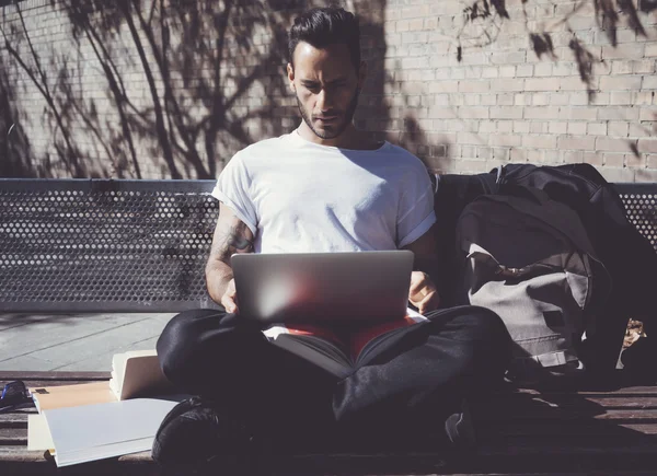 Foto hombre sentado banco del parque de la ciudad y texto cuaderno de mensajes. Uso de Internet inalámbrico. Estudiar en la Universidad, preparación para los exámenes. Utilice el libro, portátil de diseño genérico. Simulación horizontal para arriba —  Fotos de Stock