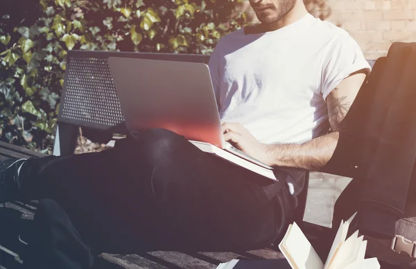 Photo homme assis banc de parc de la ville et carnet de messages texte. Utilisation d'Internet sans fil. Étudier à l'Université, préparation aux examens.Utiliser livre, ordinateur portable de conception générique. Horizontal, gros plan — Photo