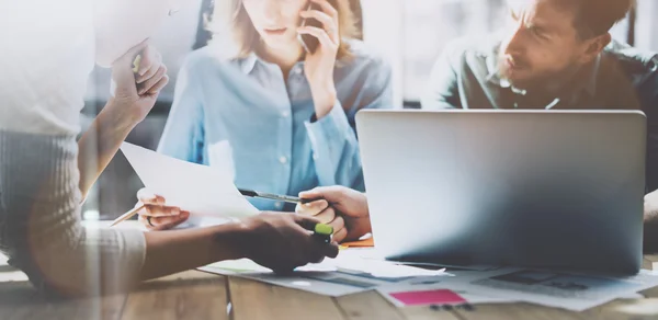 Team succes. Photo young business managers  working with new startup project in modern loft. Analyze plans. Generic design notebook on wood table, talking smartphone, papers, documents. Wide, sunlight — Stock Photo, Image