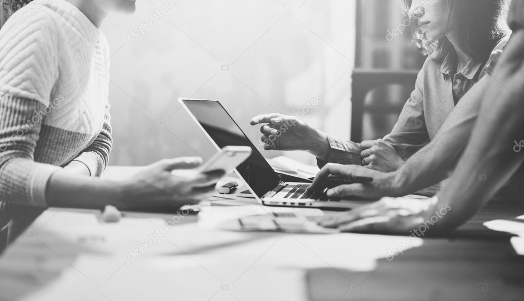 Team job succes.Photo young business managers  working with new startup project in modern loft.Analyze plans.Generic design notebook on wood table,talking smartphone, papers, documents.Black White