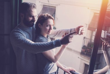 Young couple summer vacation. Photo woman and bearded man making selfie mobile phone in modern loft. Using contemporary smartphone. Horizontal, film effect. Blurred background