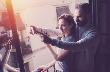 Young couple summer holiday. Photo woman and bearded man making selfie mobile phone in modern loft. Using contemporary smartphone. Horizontal, film effect. Blurred background