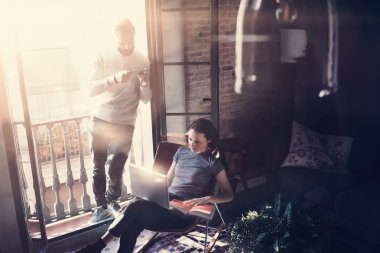 Çift profesyoneller birlikte çalışır. Fotoğraf kadın ve sakallı adam modern binada yeni başlangıç projesi ile çalışıyor. Çağdaş dizüstü bilgisayar, akıllı telefon kullanma. Yatay, film efekti. Bulanık arka plan
