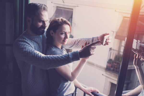 Молодая пара летние каникулы. Фото женщина и бородатый мужчина делают селфи мобильный телефон в современном лофте. Используя современный смартфон. Горизонтальный, эффект пленки. Размытый фон
