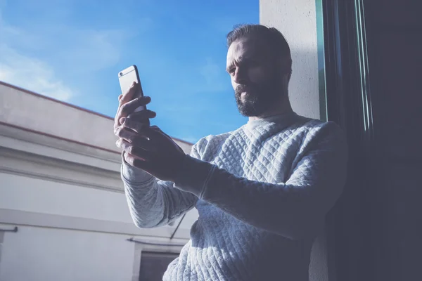 Foto bärtiger Mann macht Selfie-Handy. Mann mit zeitgenössischem Smartphone, blauer Himmel, sonniger Tag. horizontal, Filmeffekt — Stockfoto
