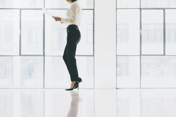 Närbild foto business kvinna som bär kostym. Öppet utrymme loft kontor. Hålla papper händer. Analysera planer, möte, panoramafönster bakgrund. Horisontella mockup. — Stockfoto