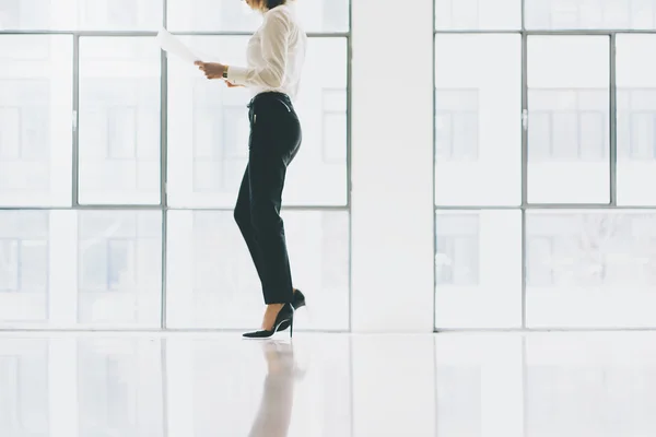 Wanita bisnis foto closeup mengenakan jas. Buka ruang kantor loteng. Memegang tangan kertas. Menganalisa rencana, pertemuan, latar belakang jendela panorama. Mockup horisontal . — Stok Foto