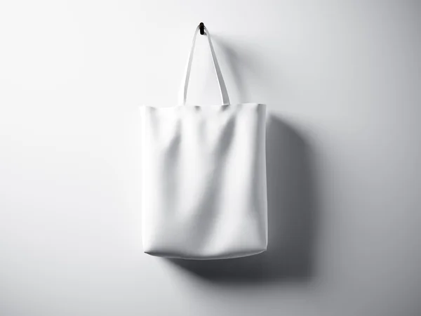 Φωτογραφία λευκό βαμβακερή τσάντα κλωστοϋφαντουργίας κρέμονται κέντρο. Κενό αφηρημένο φόντο τοίχου. Πολύ λεπτομερής υφή, Χώρος για διαφήμιση. Οριζόντια. απόδοση 3D — Φωτογραφία Αρχείου