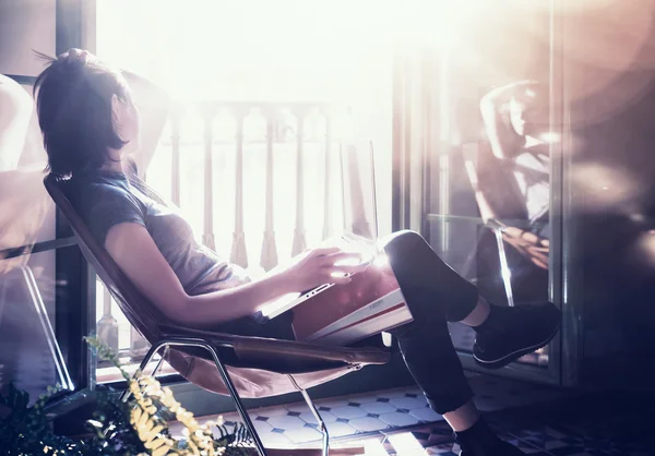 Foto giovane ragazza seduta poltrona in pelle in edificio moderno e utilizzare la connessione internet wireless portatile. Studiare all'Università, lavorare, preparare esami. Usando il libro, notebook. Rilassante. Orizzonte — Foto Stock