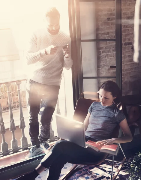 Un par de profesionales trabajan juntos. Foto mujer y hombre barbudo trabajando con un nuevo proyecto de startup en un edificio moderno. Usando cuaderno contemporáneo, teléfono inteligente.Vertical, efecto de película. Efecto de luz solar — Foto de Stock