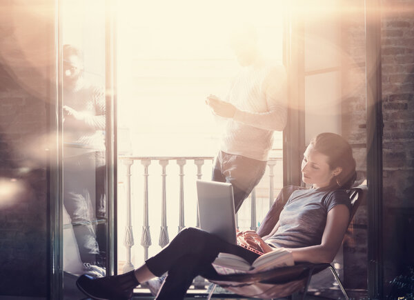 Молодая пара работает вместе. Фотоженщина и бородатый мужчина, работающие с новым фрилансерским проектом в современном здании. Использование современных ноутбуков, смартфонов. Горизонтальный, эффект пленки. Размытый фон
