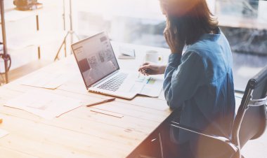 Hesap yöneticisi çalışıyor. Fotoğraf genç iş kadını ofiste yeni başlangıç projesi ile çalışır. Cep telefonu konuşuyor, mesaj yaz. Laptop ahşap masa, fincan kahve, belgeler. Yatay, bulanık. Film efekti