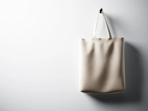 Фотография черного хлопка текстильная сумка висит в правой стороне. Пустая белая стена. Высокодетальная текстура, пространство для бизнес-сообщений. Горизонтально. 3D рендеринг — стоковое фото
