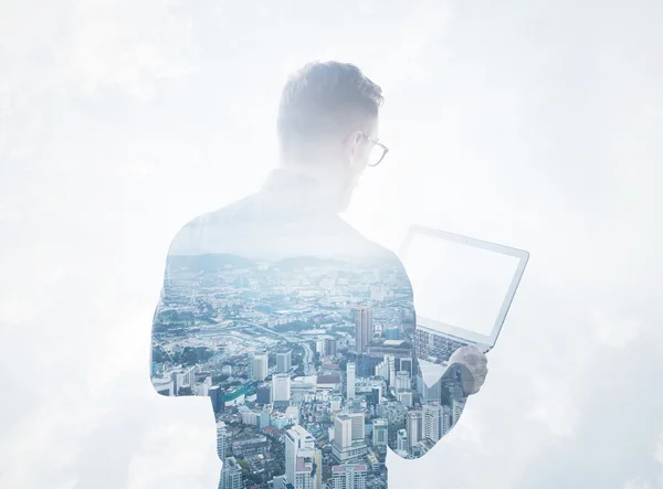 Double exposure young bearded businessman wearing black shirt holding contemporary notebook.Isolated white clouds,modern city background.Blank screen ready for your business message.Horizontal mockup — Stock Photo, Image