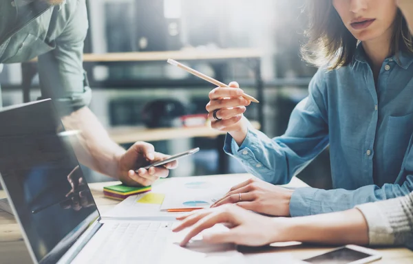 Processo de co-trabalho. Foto jovem equipe de negócios trabalhando com novo projeto de startup. Caderno sobre mesa de madeira. Mulher mostrando laptop tela, homem segurando smartphone. Fundo desfocado, efeito de filme. Horizontal — Fotografia de Stock