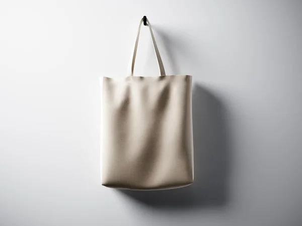 Fénykép természetes színű pamut táska lóg a közepén. Üres, fehér falháttér. Rendkívül részletes textúra, hely az üzleti üzenet. Vízszintes. 3D-leképezés — Stock Fotó