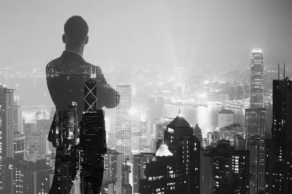 Foto de homem de negócios adulto elegante vestindo terno moderno e olhando cidade noturna. Exposição dupla, vista panorâmica contemporânea do fundo da cidade. Horizontal, bokeh, turva. Preto, branco — Fotografia de Stock