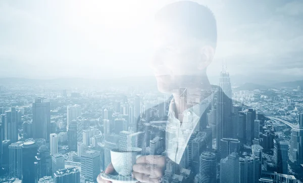 Photo d'un homme d'affaires adulte élégant portant un costume tendance et tenant une tasse de café. Double exposition, vue panoramique ville contemporaine. Horizontal — Photo